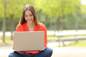 Female student working with laptop and smiling