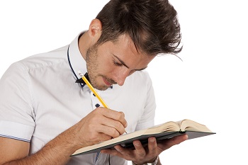 Male student carefully annotating a book with a pencil