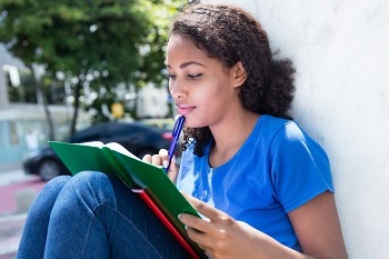 Female student sitting outside and studying a book